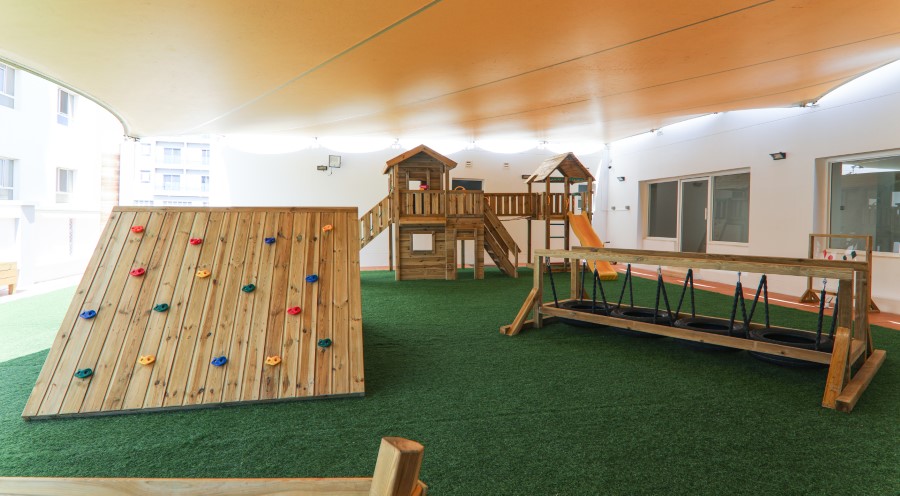 Covered outdoor play area with climbing frame and swings